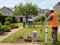Un géomètre utilise un théodolite pour un plan de bornage. Une borne cadastrale marque la limite de propriété.