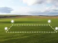 Champ verdoyant avec des repères pour délimiter une parcelle, évoquant le cadastre de Millau.
