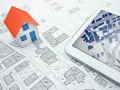Maquette de maison sur un plan cadastral, avec une tablette affichant une carte numérique. Idéal pour un projet immobilier à plu Ajaccio.