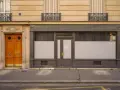 Une porte de commerce grise et une porte d'entrée en bois ornent cette façade parisienne.