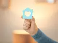 Main d'une personne tenant une maison bleue avec un cœur, symbole d'un projet de reprise de bail logement social.