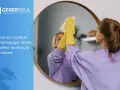 Une personne nettoie un miroir, reflétant la question de la retenue sur caution pour nettoyage.