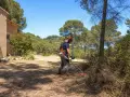 Un homme équipé pour le débroussaillement travaille près d'une maison, dans un paysage boisé. La jurisprudence débroussaillement est essentielle pour la prévention des incendies.