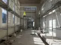 Chantier intérieur avec échafaudages, un gilet jaune suspendu, des matériaux de construction et des ouvertures. Un **daact non conforme** pourrait être la raison de cette scène.