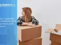 Une femme souriante près de cartons de déménagement. La question du délai de restitution du dépôt de garantie, conforme à l'article 22 de la loi n° 89-462 du 6 juillet 1989, est mise en avant.