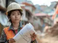 Jeune femme en casque et gilet orange, plans à la main, prête à prouver la construction de plus de 10 ans.