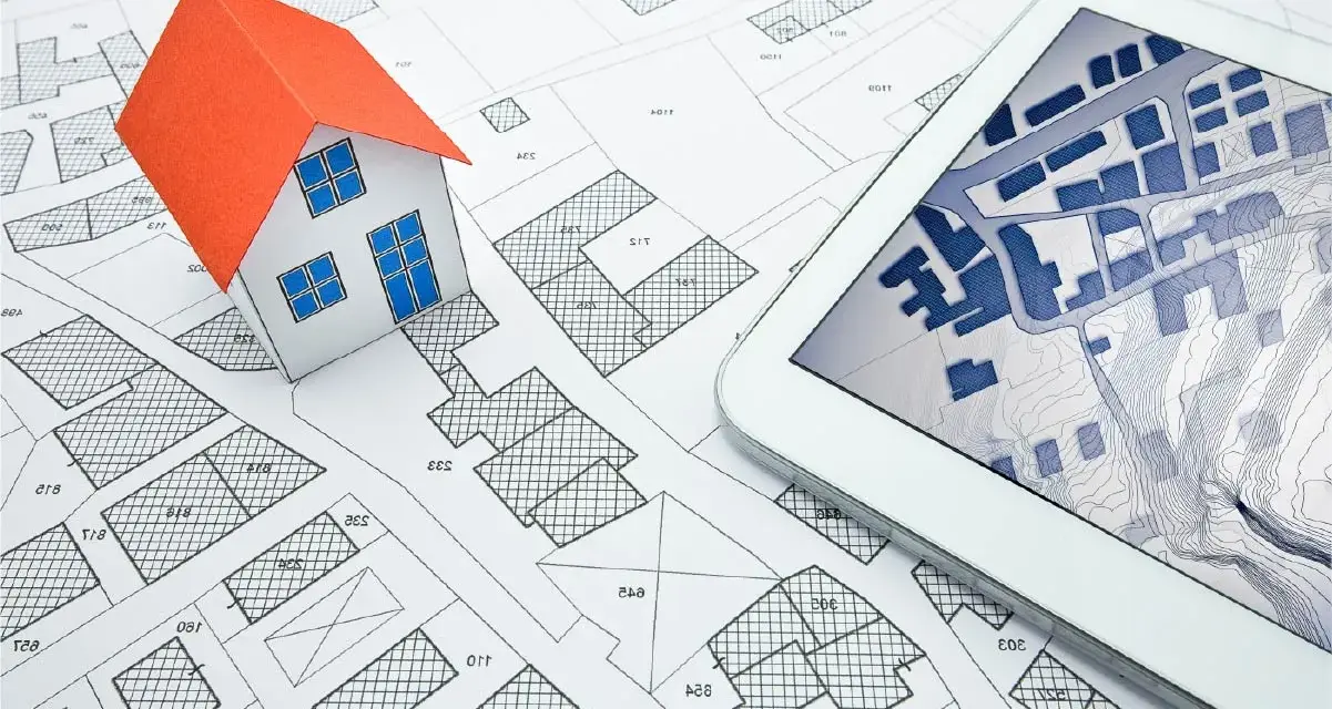 Maquette de maison sur un plan cadastral, avec une tablette affichant une carte numérique. Idéal pour un projet immobilier à plu Ajaccio.