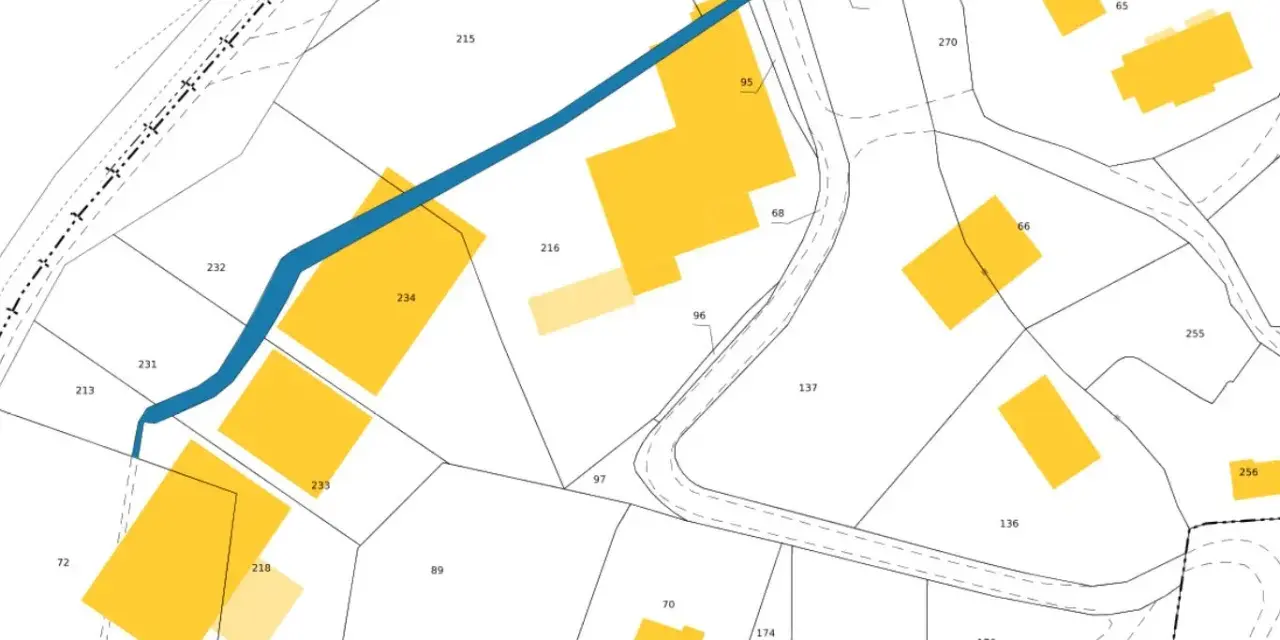 Extrait du cadastre de Lisieux, plan montrant des parcelles numérotées et des bâtiments en jaune, traversé par une rivière bleue.