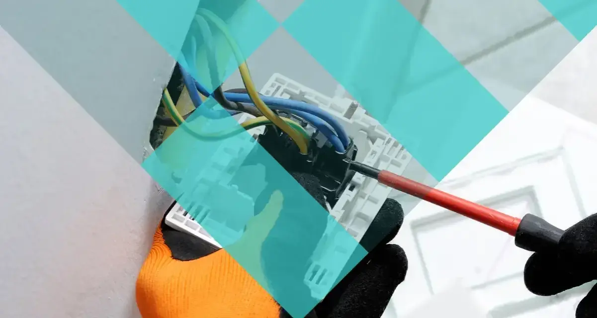 Main d'un électricien avec un tournevis, travaillant sur un tableau électrique. Projet d'urbanisme à Marcq-en-Barœul.