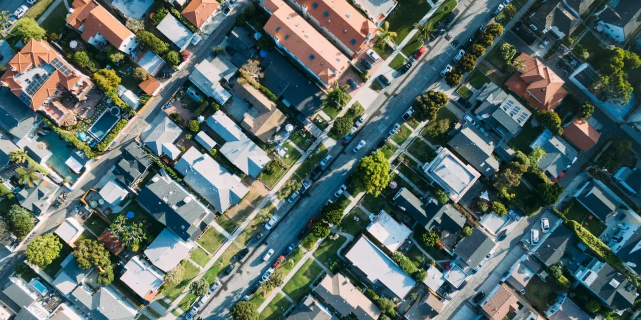 Vue aérienne d'un quartier résidentiel, avec des maisons aux toits de tuiles et des rues bordées d'arbres, rappelant l'application du l442-10 code urbanisme.
