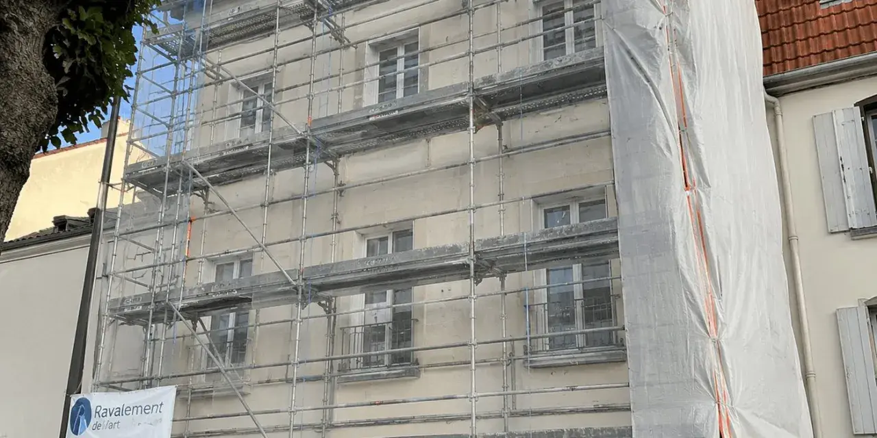 Ravalement de façade en cours, échafaudages recouvrant le bâtiment. Une bâche blanche protège une partie des travaux. L'indemnisation locataire est une préoccupation lors de ces rénovations.