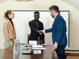 Trois personnes en tenue d'affaires se serrent la main. L'un d'eux discute des intérêts d'un compte séquestre notaire.