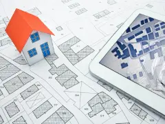 Maquette de maison sur un plan cadastral, avec une tablette affichant une carte numérique. Idéal pour un projet immobilier à plu Ajaccio.