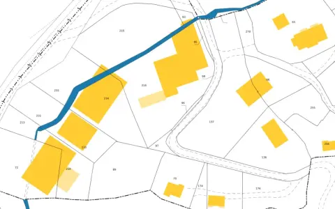 Extrait du cadastre de Lisieux, plan montrant des parcelles numérotées et des bâtiments en jaune, traversé par une rivière bleue.