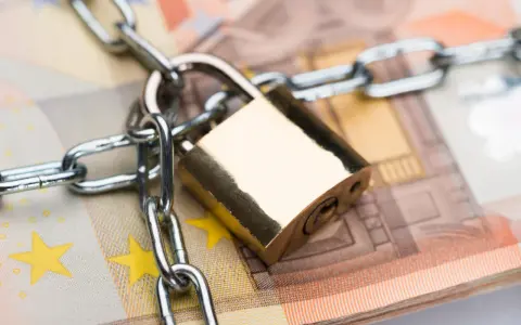 Un cadenas et une chaîne sécurisent des billets en euros, symbolisant la consignation de loyer ou la protection de fonds.