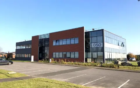 Bâtiment moderne avec façade vitrée et panneaux marron, arborant le logo GSE. Un parking est visible devant, près de Villeneuve d'Ascq.
