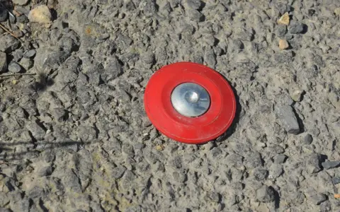 Borne rouge sur le sol, marquant un point pour le cadastre de Tarascon.
