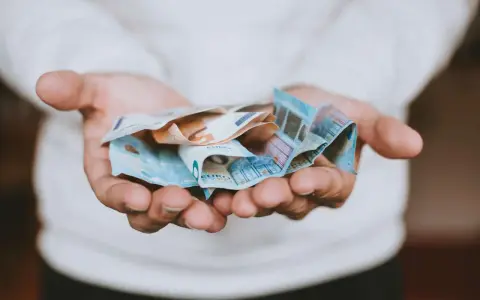 Mains tenant des billets en euros froissés, évoquant une transaction financière, peut-être une donation déguisée ou un viager.