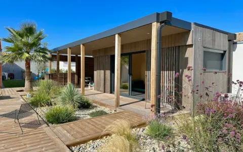Une maison en bois moderne avec terrasse et jardin, une construction sans permis de construire idéale pour un espace de vie contemporain.