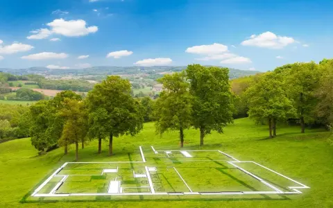 Plan d'une maison superposé sur un terrain verdoyant, illustrant la constructibilité d'un terrain. Paysage bucolique sous un ciel bleu.