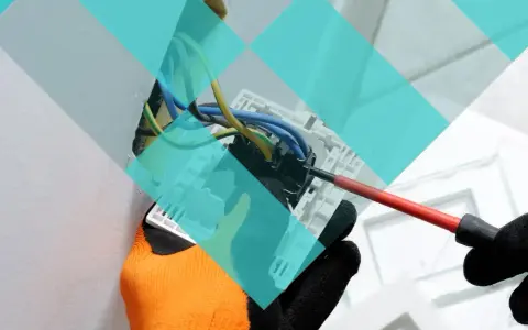 Main d'un électricien avec un tournevis, travaillant sur un tableau électrique. Projet d'urbanisme à Marcq-en-Barœul.