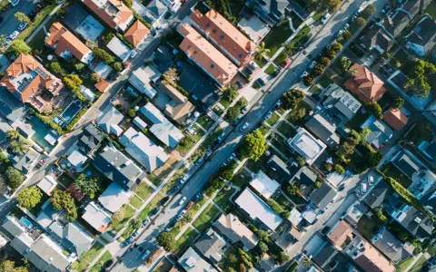 Vue aérienne d'un quartier résidentiel, avec des maisons aux toits de tuiles et des rues bordées d'arbres, rappelant l'application du l442-10 code urbanisme.