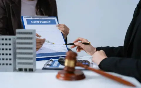Deux mains signent un contrat immobilier, évoquant le droit de rétractation. Une maquette d'immeuble est visible.