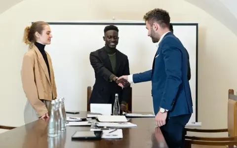 Trois personnes en tenue d'affaires se serrent la main. L'un d'eux discute des intérêts d'un compte séquestre notaire.
