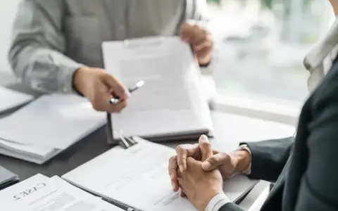 Deux personnes discutent d'un document, peut-être une clause tontine, lors d'une réunion formelle.