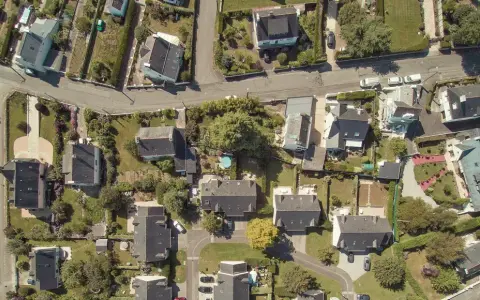 Vue aérienne d'un quartier résidentiel, avec des maisons aux toits sombres et des jardins verdoyants. Le cadastre noisy le sec révèle l'organisation des parcelles.