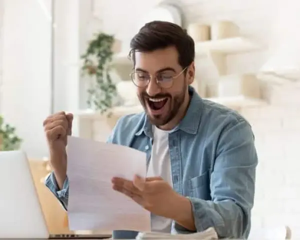 Homme joyeux, poing levé, découvrant une bonne nouvelle sur un document, peut-être la rémunération gérant SCI.