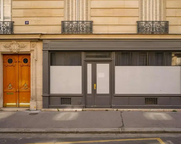 Une porte de commerce grise et une porte d'entrée en bois ornent cette façade parisienne.