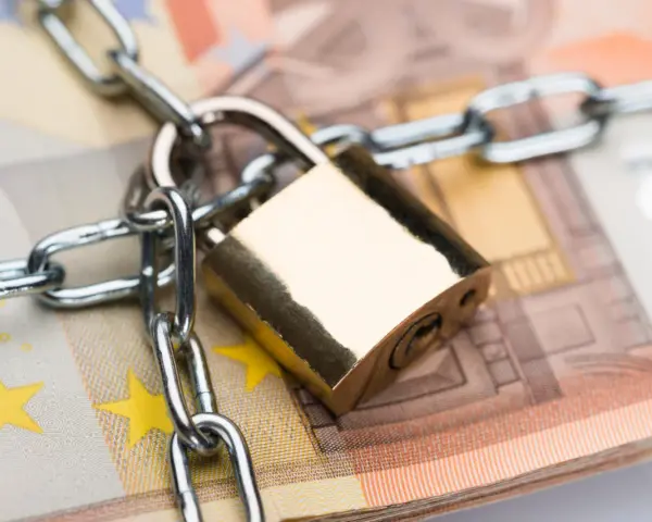 Un cadenas et une chaîne sécurisent des billets en euros, symbolisant la consignation de loyer ou la protection de fonds.