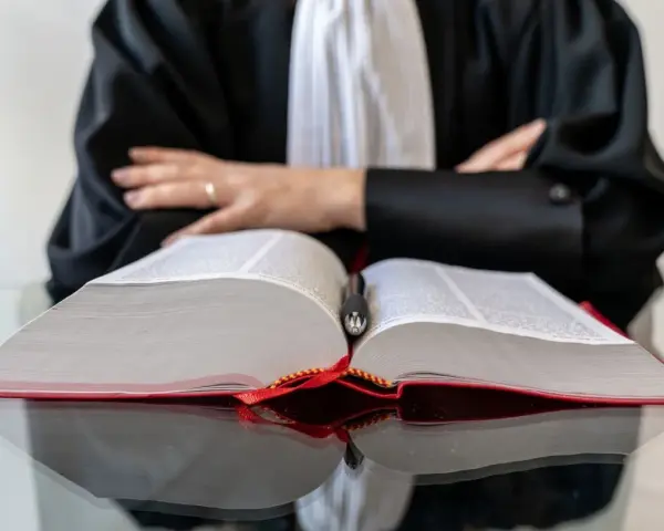 Un avocat en robe noire, penché sur un gros livre ouvert, symbolise la **notoriété acquisitive** par la maîtrise du droit.