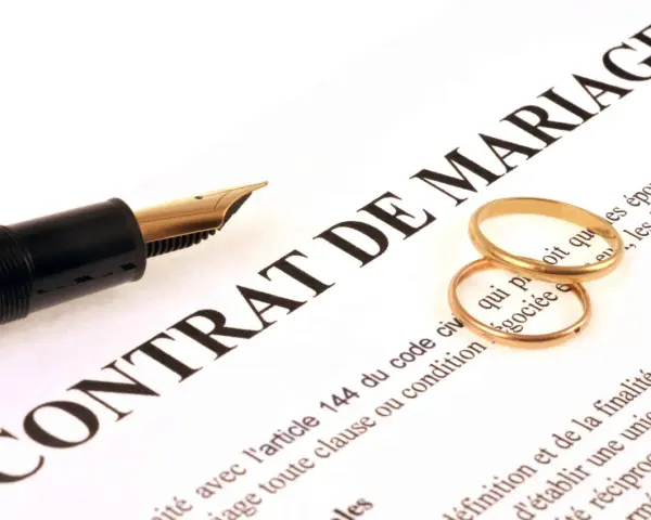 Plume et alliances sur un contrat de mariage, symbolisant une union et une récompense travaux d'amélioration.