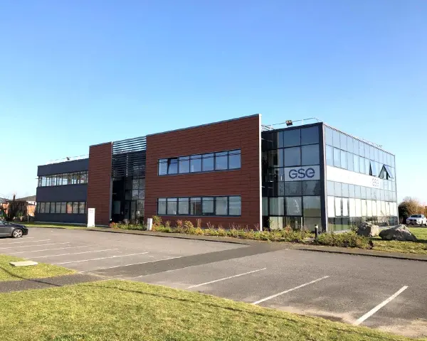 Bâtiment moderne avec façade vitrée et panneaux marron, arborant le logo GSE. Un parking est visible devant, près de Villeneuve d'Ascq.