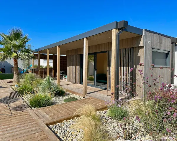 Une maison en bois moderne avec terrasse et jardin, une construction sans permis de construire idéale pour un espace de vie contemporain.