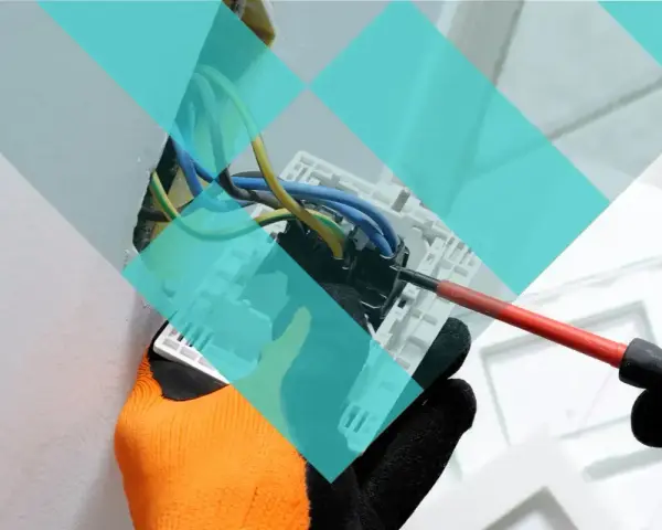 Main d'un électricien avec un tournevis, travaillant sur un tableau électrique. Projet d'urbanisme à Marcq-en-Barœul.