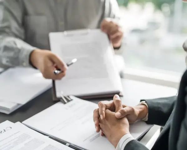 Deux personnes discutent d'un document, peut-être une clause tontine, lors d'une réunion formelle.