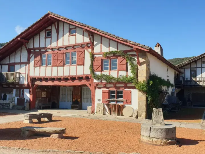 Maison basque traditionnelle à colombages rouges et blancs, avec un puits ancien devant. Un lieu plein de charme à Saint-Pée-sur-Nivelle.