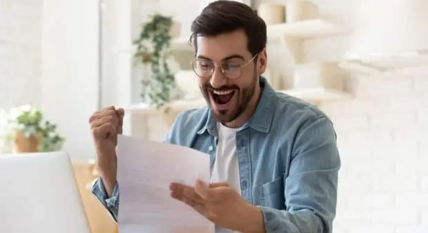 Homme joyeux, poing levé, découvrant une bonne nouvelle sur un document, peut-être la rémunération gérant SCI.