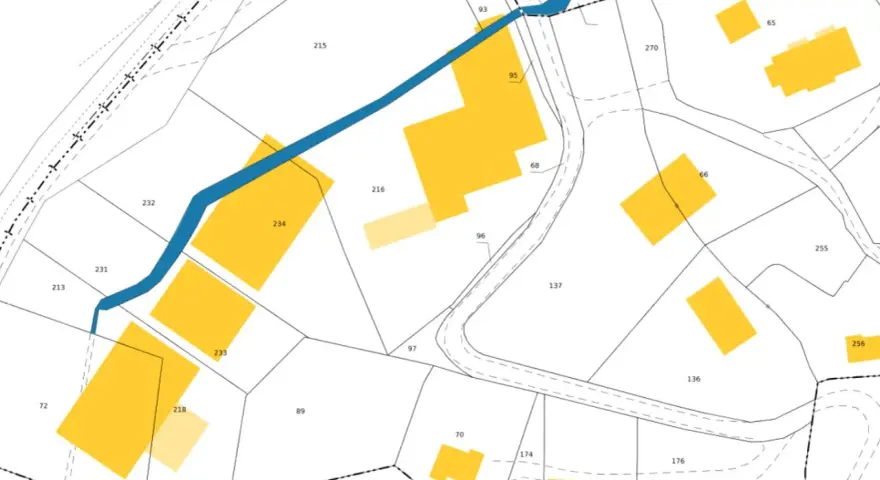 Extrait du cadastre de Lisieux, plan montrant des parcelles numérotées et des bâtiments en jaune, traversé par une rivière bleue.