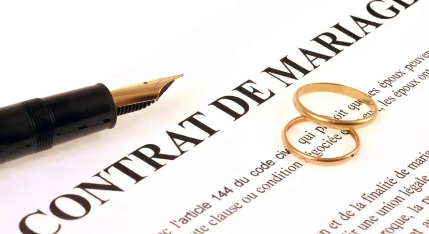 Plume et alliances sur un contrat de mariage, symbolisant une union et une récompense travaux d'amélioration.