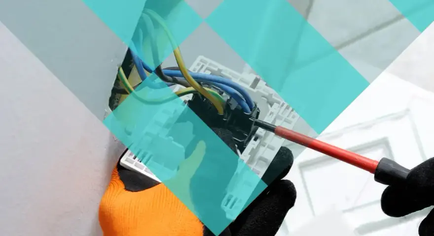 Main d'un électricien avec un tournevis, travaillant sur un tableau électrique. Projet d'urbanisme à Marcq-en-Barœul.