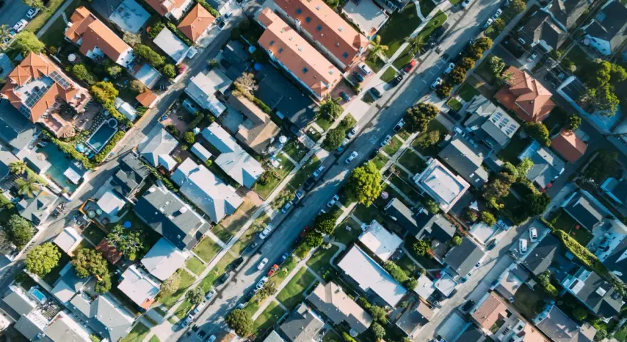 Vue aérienne d'un quartier résidentiel, avec des maisons aux toits de tuiles et des rues bordées d'arbres, rappelant l'application du l442-10 code urbanisme.