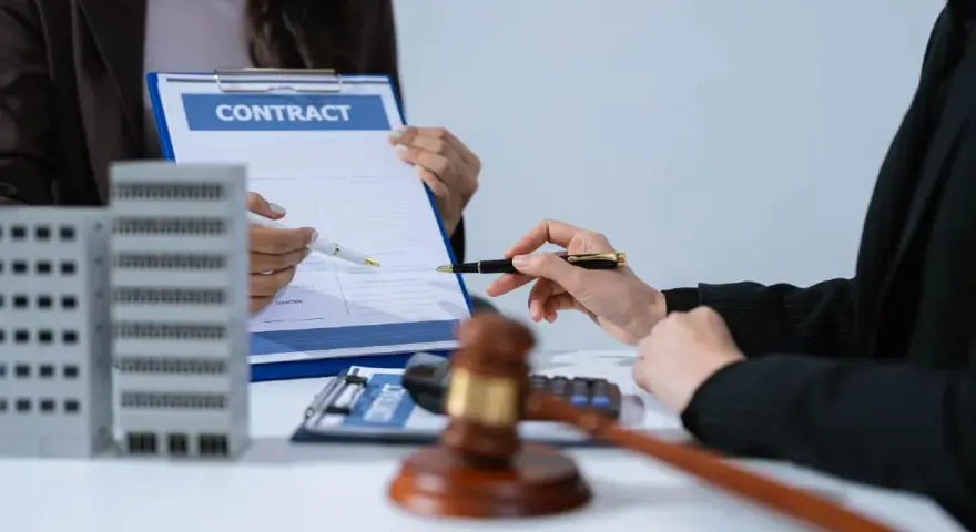 Deux mains signent un contrat immobilier, évoquant le droit de rétractation. Une maquette d'immeuble est visible.