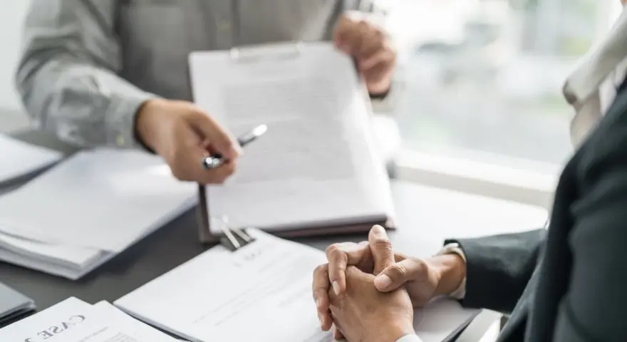 Deux personnes discutent d'un document, peut-être une clause tontine, lors d'une réunion formelle.