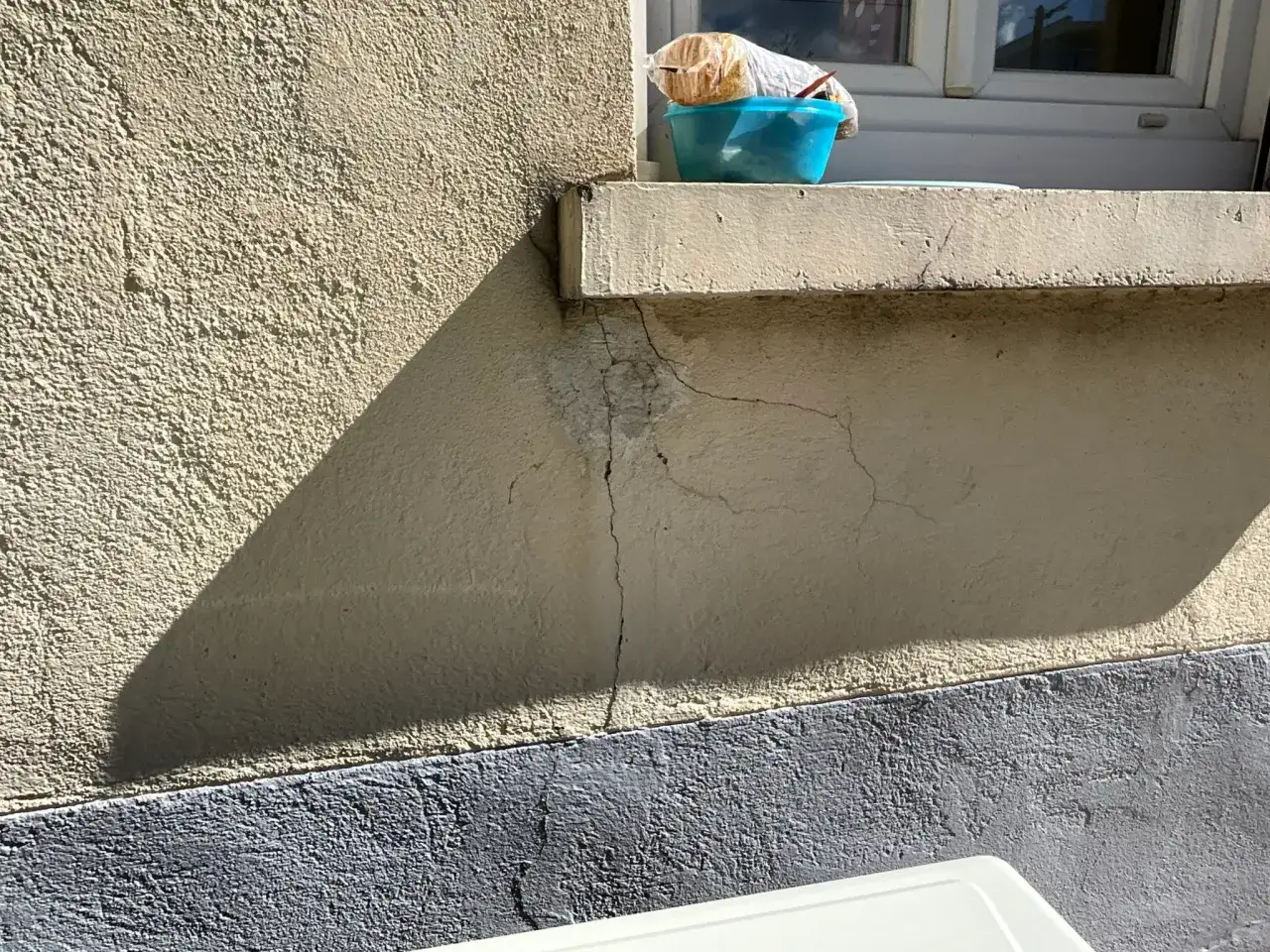 Fissures sur un mur ext&eacute;rieur, pr&egrave;s d'une fen&ecirc;tre. Un pot bleu contient un objet emball&eacute;. Un cas de prescription vice cach&eacute; ?