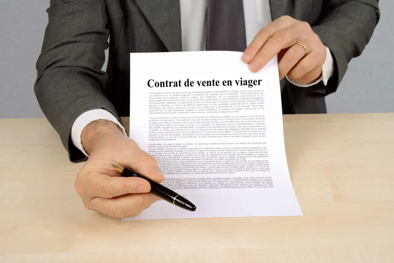 Un homme en costume gris pr&eacute;sente un contrat de vente en viager, soulignant l'avantage du viager pour le vendeur.