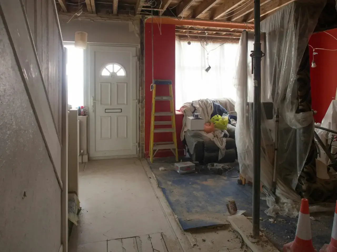 Intérieur en chantier, porte blanche, escalier, meubles recouverts, échafaudage. Travaux de ravalement de façade, indemnisation locataire en cours.